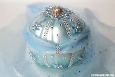 a blue ornament sitting on top of a white plate covered in crystal beads