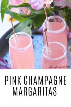 two pink champagne margaritas sitting on top of a tray with flowers in the background