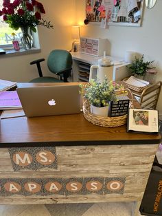 a desk with a laptop on top of it next to a potted plant and books