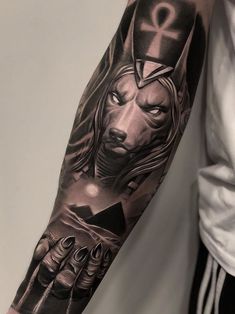 a man's arm with a wolf tattoo on it, and an egyptian symbol