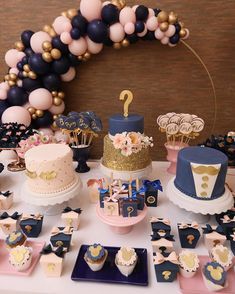 a table topped with cakes and cupcakes on top of plates next to balloons