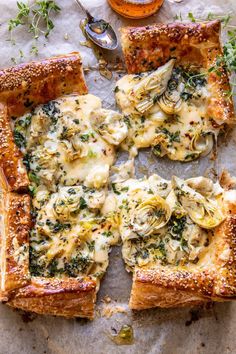 a pizza with artichokes and cheese on it is cut into four pieces