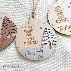 three wooden christmas ornament hanging on a white blanket with snowflakes and pine trees