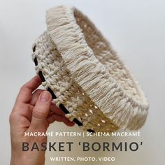 a hand is holding up a basket with yarn on it and the words,'basket bormio'written in white