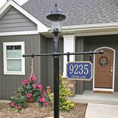 An example address plaque post assembly with a post-top light, a hanging flower basket on one side, and the hanging address plaque on the other side, all in front of a grey house Small Yard Curb Appeal, Address Sign Post, Number Plate Design, Curb Appeal Garden, Curb Appeal Landscape, Add Curb Appeal, Front Yards Curb Appeal, Porch Landscaping, Landscape Curbing