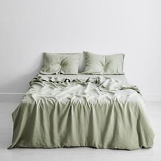 an unmade bed with green sheets and pillows