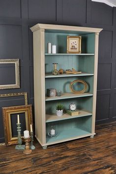 an empty bookcase in the corner of a room next to a framed photograph and other items