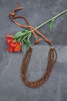 Need an eye catching piece that sparkles in the sunlight? Look no farther! This stunning brown crystal necklace has glass brown seed beads and brown "crystals" that make up a total of 8 strands on a sturdy leather cord. Makes a wonderful statement piece for those extra special occasions. This necklace was constructed in Thailand by at-risk and rescued women.  Dimensions: 52.5" L . Brown Beaded Multi-strand Jewelry, Brown Multi-strand Beaded Necklace With Gold Beads, Brown Gold Beads Multi-strand Necklace, Brown Multi-strand Necklace With Polished Beads, Adjustable Brown Crystal Necklace With Polished Beads, Multi-strand Brown Jewelry With Polished Beads, Brown Faceted Beads Jewelry For Party, Brown Multi-strand Beaded Necklaces, Brown Multi-strand Party Jewelry