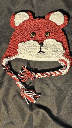 a crocheted hat with a red fox face on the front and white ears