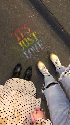 two people standing next to each other with their feet on the ground and writing in chalk