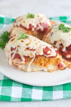 two stuffed meatballs covered in sauce and cheese on a white plate