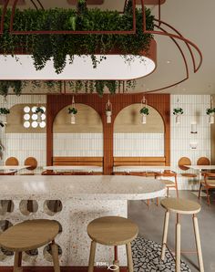 the interior of a restaurant with tables, stools and potted plants hanging from the ceiling