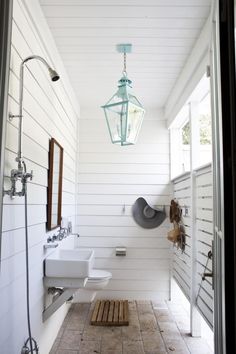 a bathroom with white walls and wood flooring next to a light hanging from the ceiling