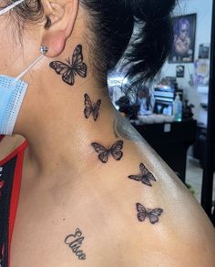 a woman wearing a face mask with butterflies on her neck and behind her ear tattoo