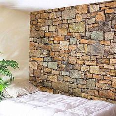 a bedroom with a stone wall next to a bed and potted plant in the corner