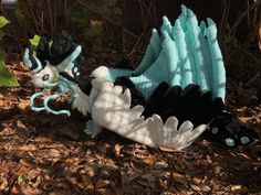 a crocheted dragon laying on the ground