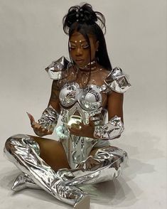 a woman dressed in silver sitting on the ground