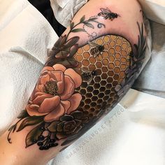 a woman's arm with flowers and honeycombs on it