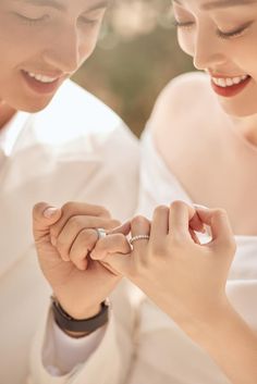 a man and woman holding hands while looking at each other's wedding rings on their fingers