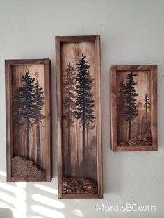 two wooden wall hangings with pine trees painted on the sides and rocks in between them