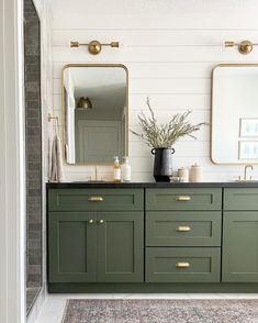 a bathroom with green cabinets and two mirrors on the wall next to a rug in front of it