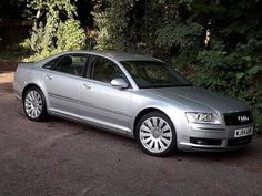 a silver car parked in front of some trees