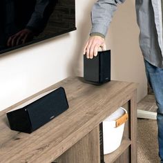 a man is standing next to a table with speakers on it and his hand reaching for the speaker