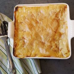 a casserole dish on a striped napkin next to silverware