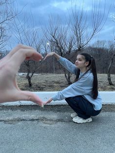 a woman reaching out her hand to touch another person's hand while sitting on the ground