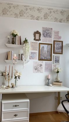 a white desk with flowers and pictures on the wall