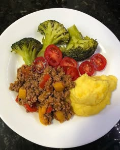 a white plate topped with meat, vegetables and mashed potatoes