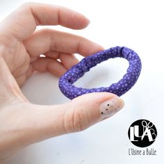 a woman's hand holding a purple bracelet with polka dots