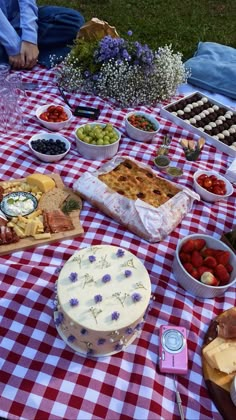 a table topped with lots of food on top of a red and white checkered table cloth