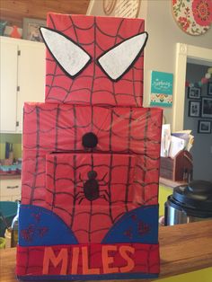 a spider man made out of cardboard sitting on top of a kitchen counter with the words miles painted on it