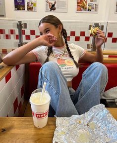 a woman sitting at a table with food and drink in front of her, while eating