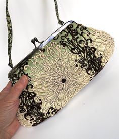 "Vintage Purse Santi Beaded Bag This gorgeous beaded bag was named The FIJI and was made in India for SANTI. This purse is a made out of a pale mint green satin or silk and is covered with an exquisite tropical pattern in pearly white and chocolate brown beads. The pattern looks like an underwater flower garden wonderful and wild with intwined curlicues and scrolls! The intricate floral beading is all over and reverses in color from front to back.  The frame is a shiny deep bronze metal color with a kiss clasp accented with two sparkling rhinestones. The interior is a very pale creamy yellow satin with one zippered pocket and one one sewn in pocket that has the signature blue and yellow fabric tag. There is a fabric handle that matches the fabric and pattern on the purse.  Measures 11\" x Green Vintage Shoulder Bag For Party, Vintage Green Shoulder Bag For Party, Green Beaded Evening Bag, Green Embroidered Evening Bag, Elegant Green Embroidered Evening Bag, Elegant Embroidered Green Evening Bag, Green Beaded Evening Shoulder Bag, Evening Green Beaded Shoulder Bag, Elegant Green Embroidered Shoulder Bag