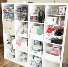 a white bookcase filled with lots of craft supplies and storage bins on top of it