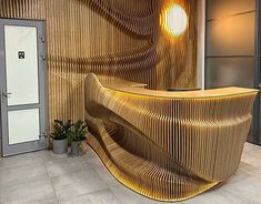 an office lobby with a curved wooden reception counter and planters on the side wall