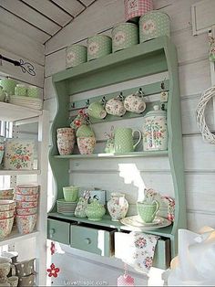 a green shelf filled with lots of dishes and cups on top of it's shelves