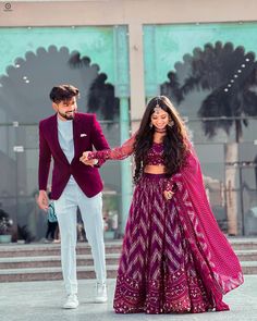 a man in a tuxedo walking next to a woman in a purple dress