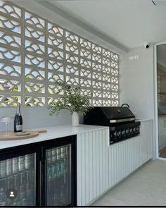 an outdoor kitchen with white cabinets and black appliances