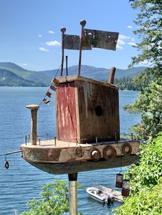 a rusted out boat sitting on top of a wooden pole next to the ocean