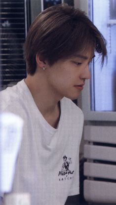 a young man sitting at a table with food in front of him and his eyes closed