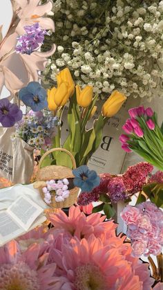 a bunch of flowers sitting on top of a table next to a book and bag