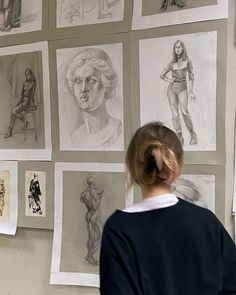 a woman looking at drawings on the wall