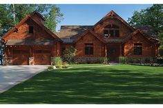 a large log home with two car garages on the front and side of it