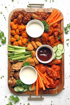 a platter filled with chicken wings, carrots, celery and cucumbers