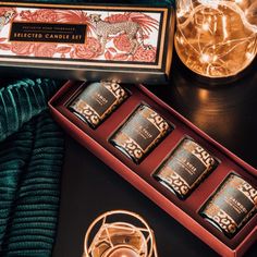 an assortment of candles and teas on a black table with green velvet material, surrounded by other decorative items