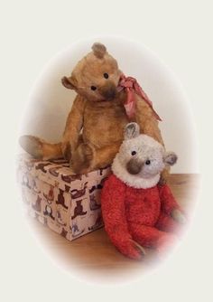 two teddy bears sitting on top of a box with another stuffed animal in the background