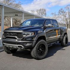 a large black truck parked in front of a parking lot next to a white building